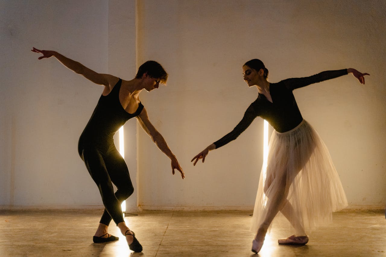 Two professional ballet dancers rehearse gracefully in a studio, showcasing elegance and skill.